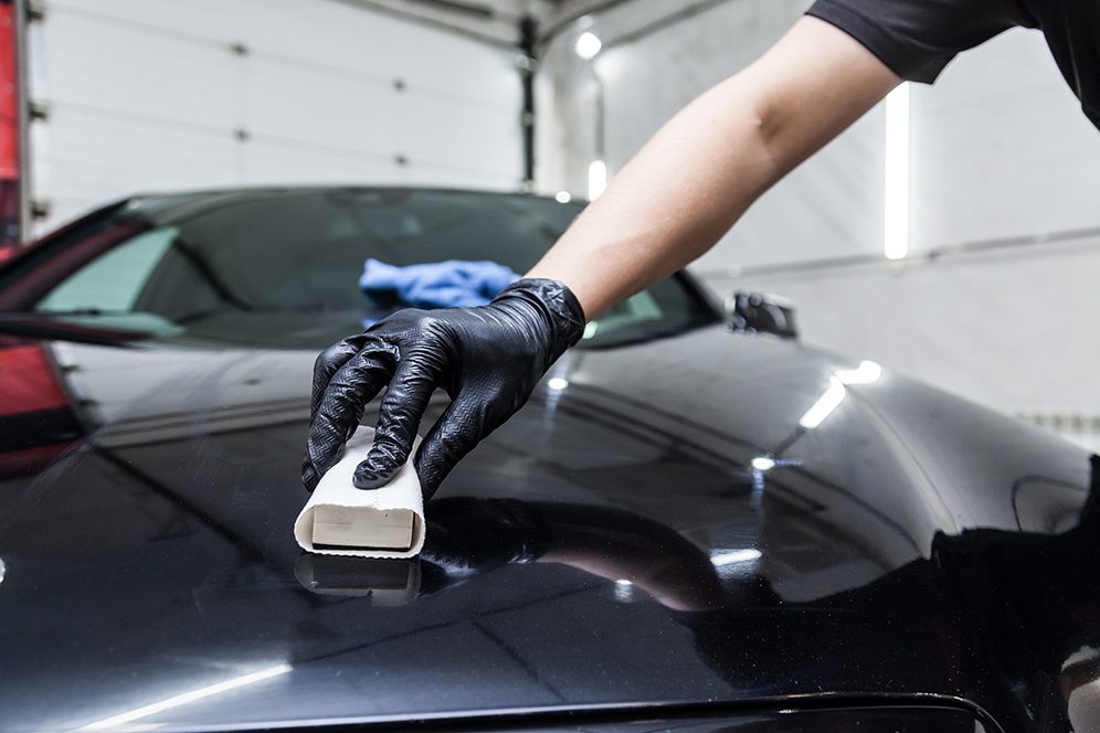 The process of applying a nano-ceramic coating on the car's hood The process of applying a nano-ceramic coating on the car's hood by a male worker with a sponge and special chemical composition to protect the paint on the body from scratches, chips and damage.